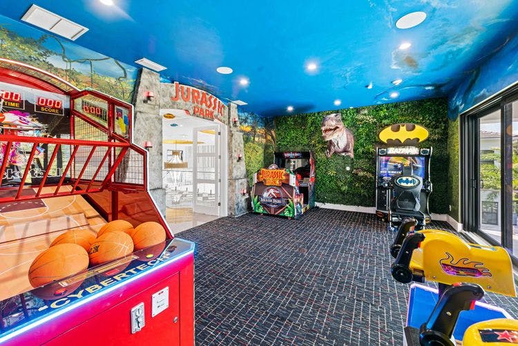 Reunion Resort 16000 villa game room with arcade machines, indoor basketball game and a t-rex emerging from the wall