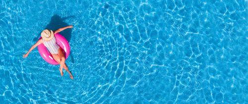 A woman lying in a pink inflatable in a pool