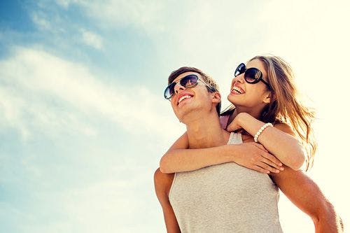 A young couple embrace under a sunny sky