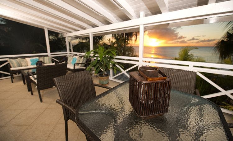 2 bedroom villas in Paynes Bay - Bora Bora Upper balcony with chairs and tables overlooking a sunset at sea