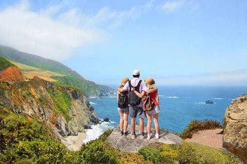 A family stands looking at the coastline in California