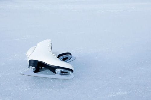 A pair of white ice skates lying on ice