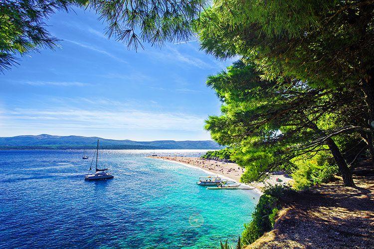 The coastline of Brac with white sand beach and sailboat