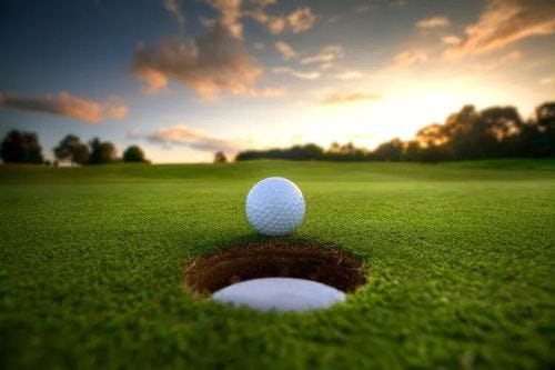 A golf ball teetering on the edge of a hole