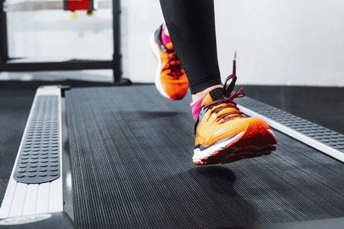 A person in orange sneakers on a treadmill
