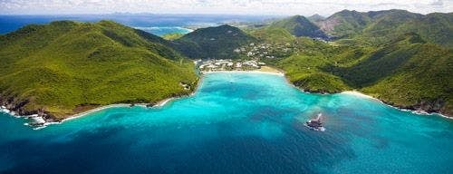 Anse Marcel bay and white sand beach surrounded by forested hills