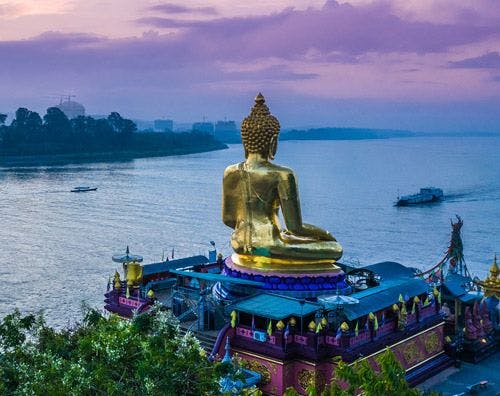 A golden buddha statue overlooking the Mekong River