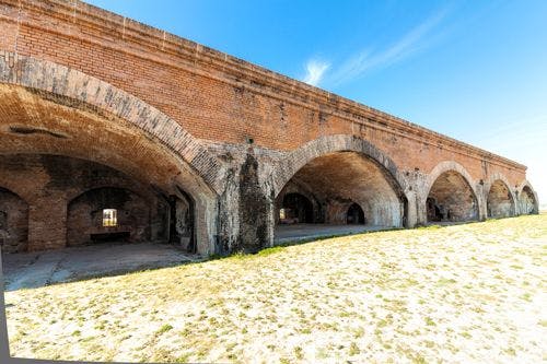 Fort Pickens historic building with stone arches on white sand