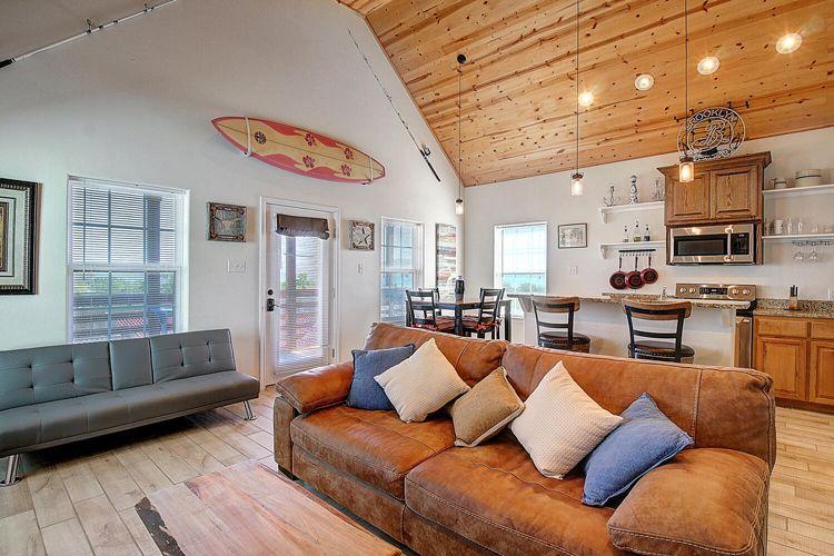 Corpus Christi beach house rentals Corpus Christi 15 lounge of villa with surfboard on the wall, kitchen-bar and brown leather sofa