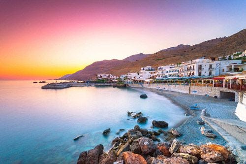 Cretan village of white buildings by the sea at sunset