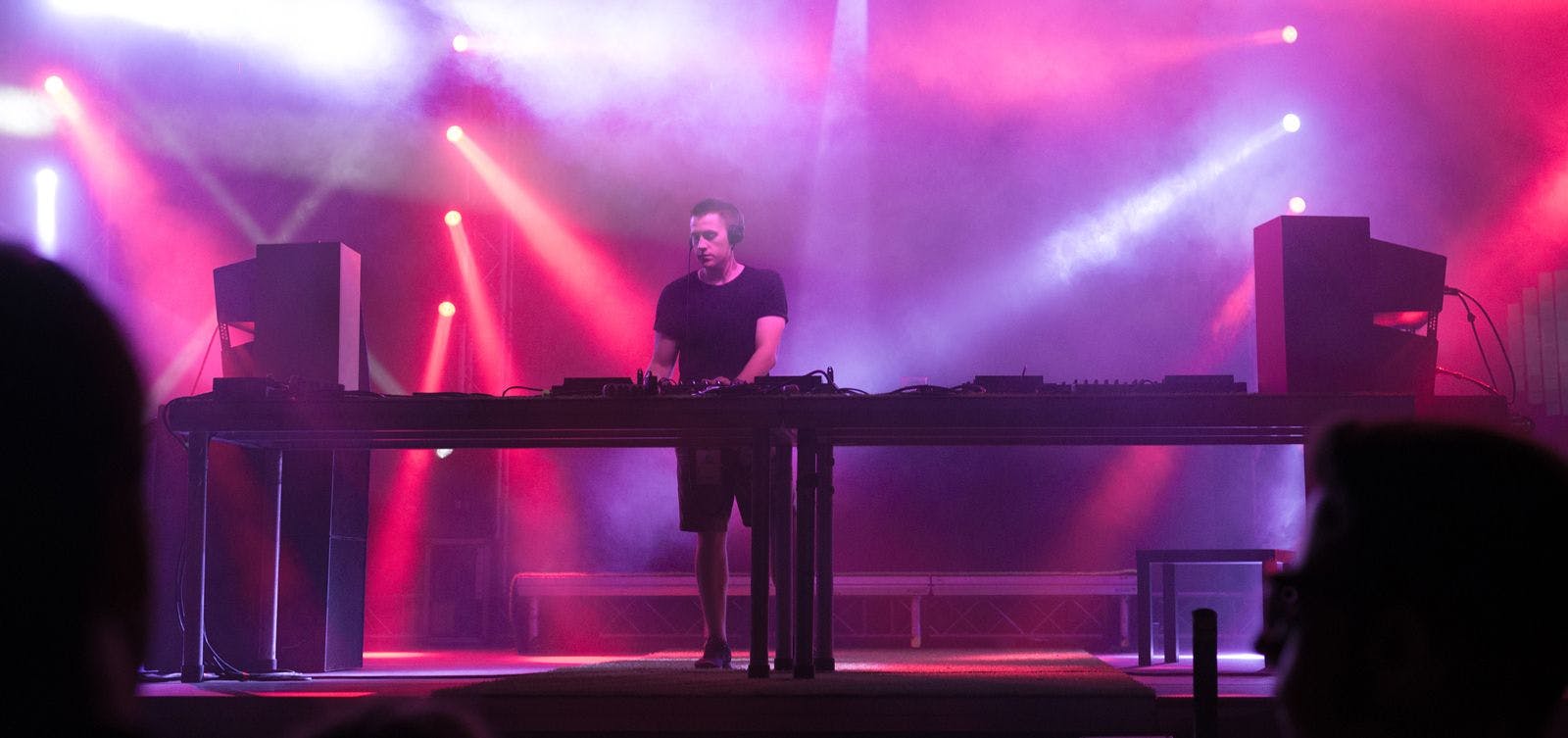 A man DJ's on stage with spotlights and smoke effects