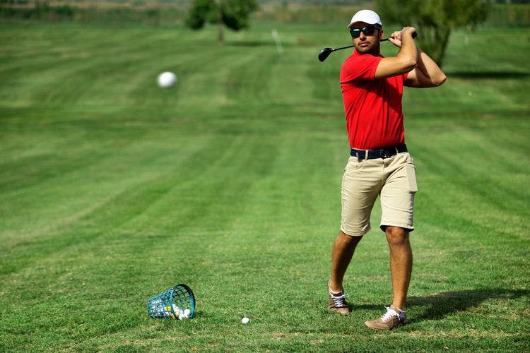 A man in a red shirt playing on a golf course in the Caribbean