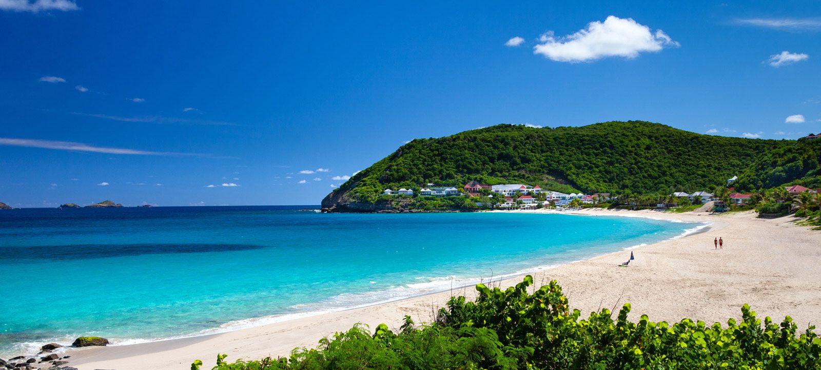 White sand beach with tree-covered hill in the background