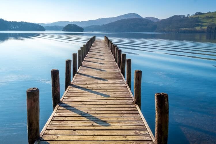 A wooden boardwalk leading out into a still, calm lake