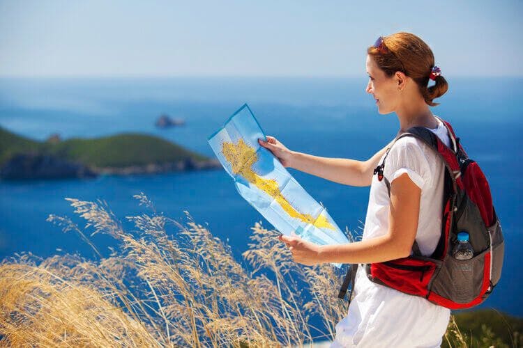 A woman surveys the island of Corfu with a map