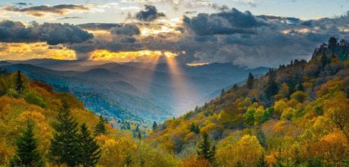 Sun breaks through the clouds over the forested slopes of the Great Smoky Moutains