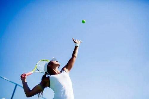 A woman serves a tennis ball