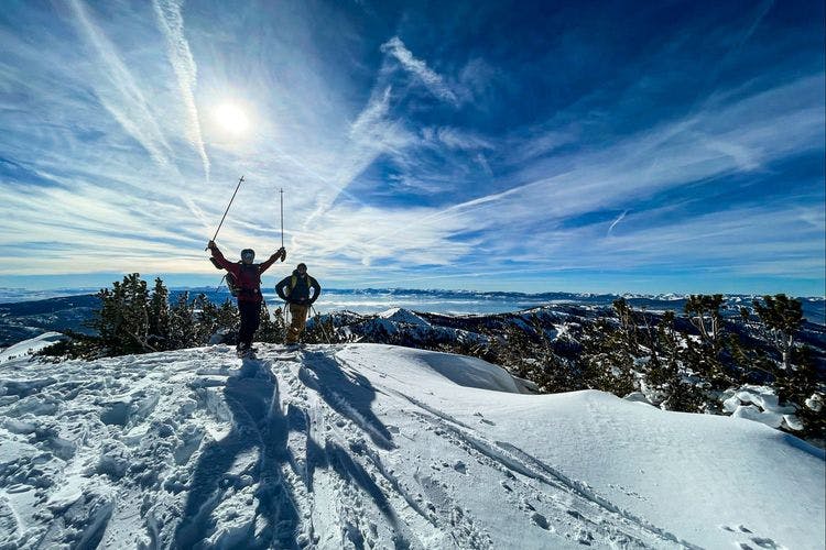 Two skiiers at the top of snowy mountain peak on Lake Tahoe