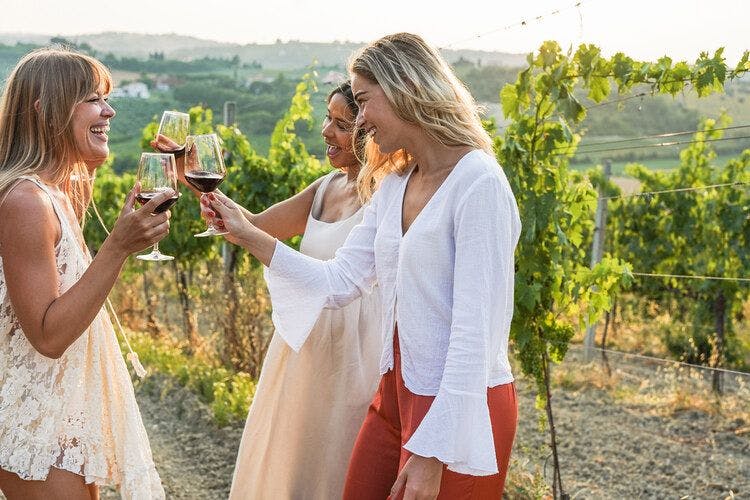 A group of female friends enjoy wine tasting in a Tuscan vineyard