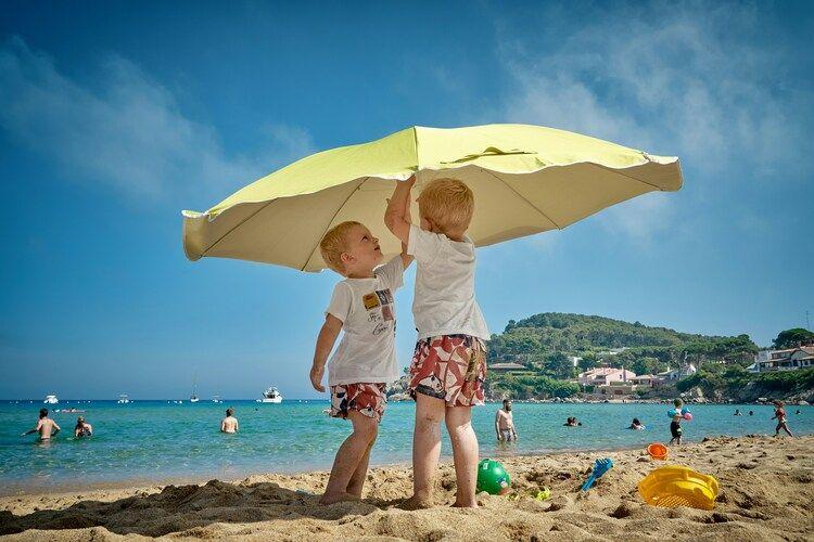Ibiza or Majorca for family holiday, beach day, boys put up a parasol on the beach, Top Villas