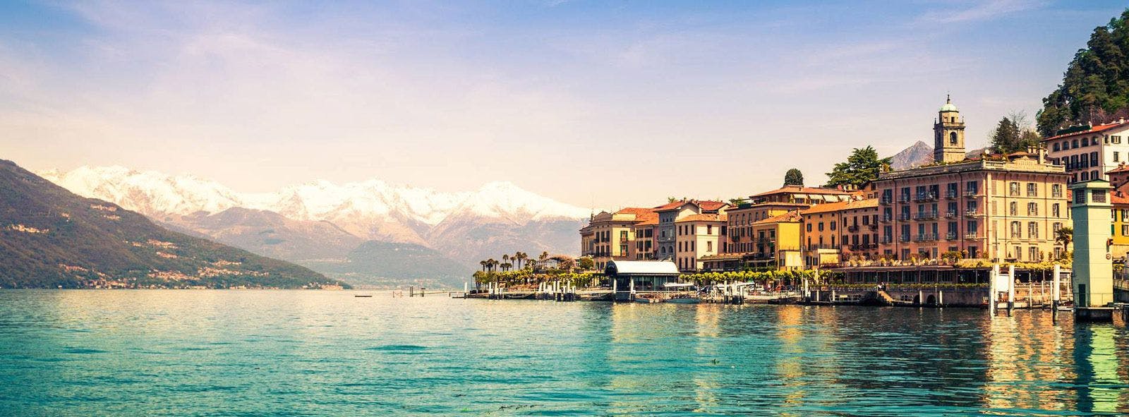 Lake Como town by the water with snow capped mountains in the distance