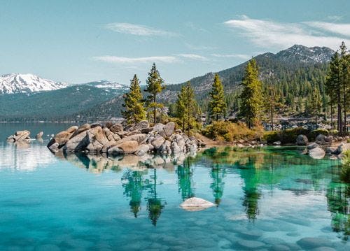 The rocky shore of Lake Tahoe with trees and mountains