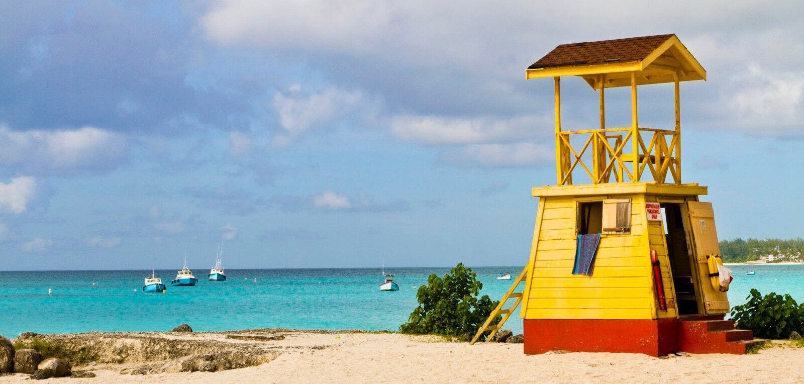 Yellow and red lifeguard station on a white sand beach