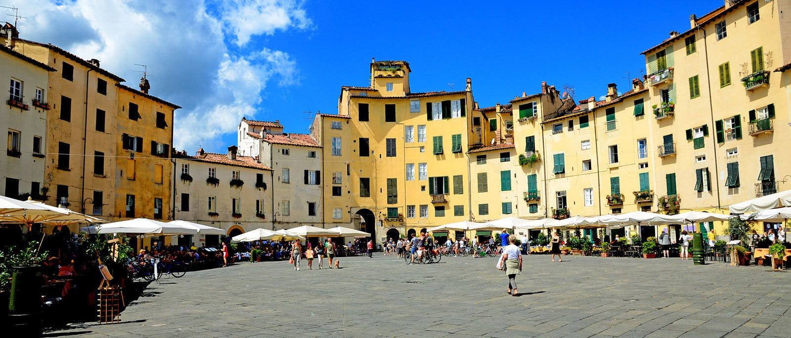 The central town square of Lucca, with yellow buildings around a central plaza