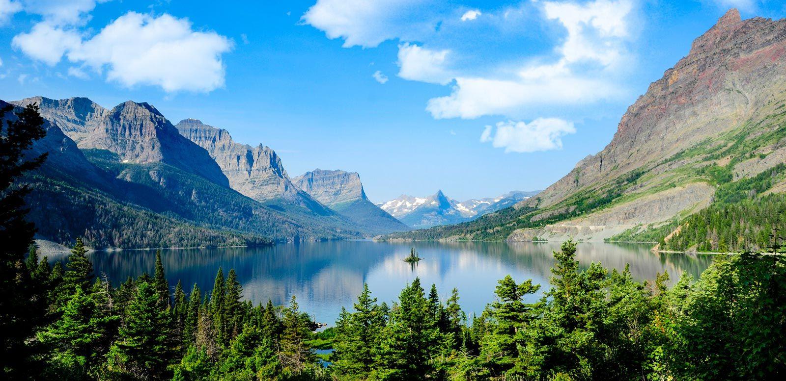 View of Glacier National Park with steep mountains, green forests and a still lake