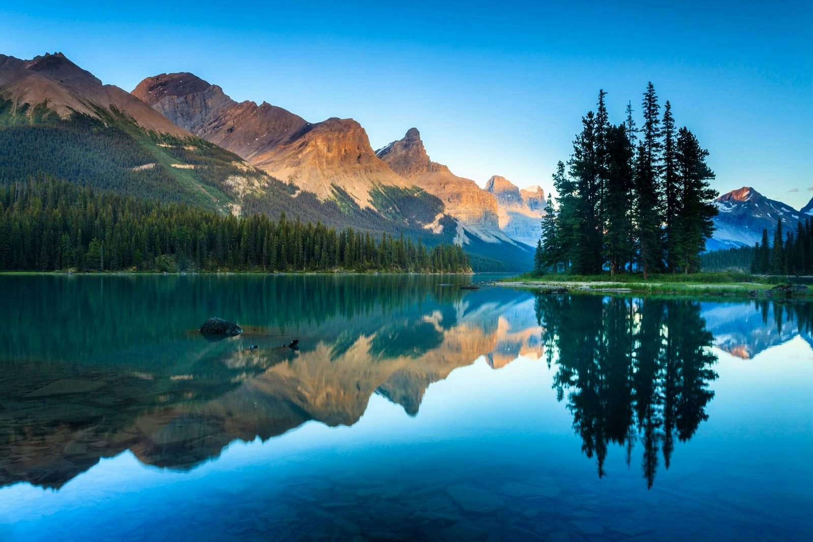 View of mountains and trees reflected in a still lake