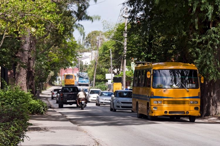 A yellow bus and cars on a Barbados road