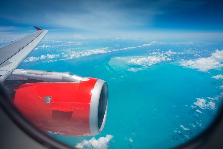 View of a plane wing and engine flying over the Caribbean Sea