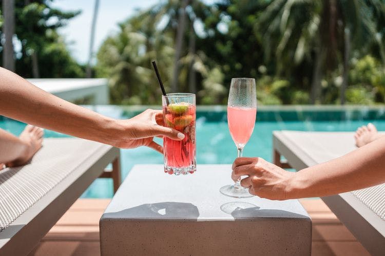 A couple enjoy a poolside cocktail at the private vacation rental nearby a pickleball court