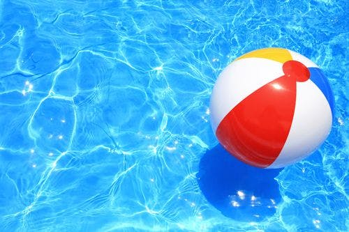 A striped, colorful beach ball floating in a pool