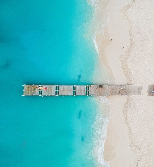Ariel shot of wooden pier on white sand beach