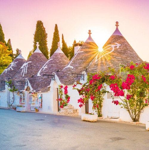 Conical trullo houses at sunset