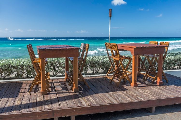 Wooden tables and chair by the sea at a restaurant in Barbados