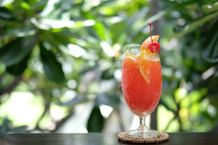 Orange rum punch in front of a rainforest backdrop