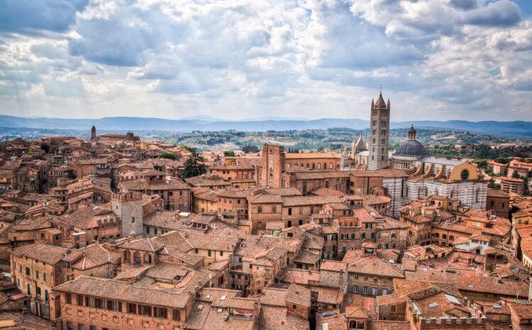 A view of the city of Siena in Tuscany with red roofed buildings and towers