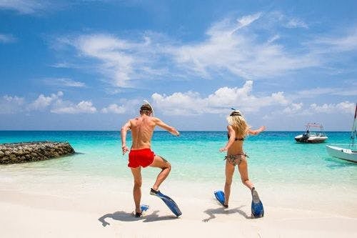 Two people in flippers running towards the sea