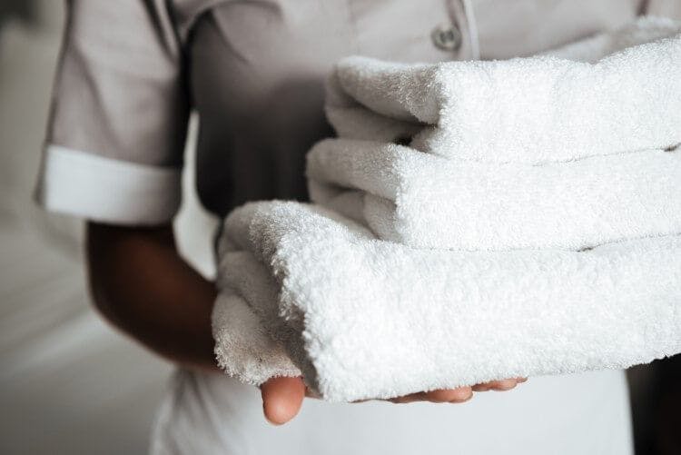 A lady housekeeper carrying a pile of fluffy white towels