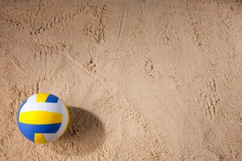 A volleyball laying on white sand