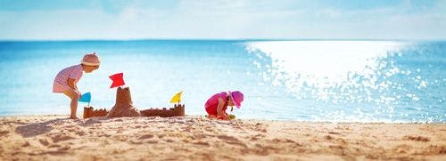 Two young children building sandcastles on a beach