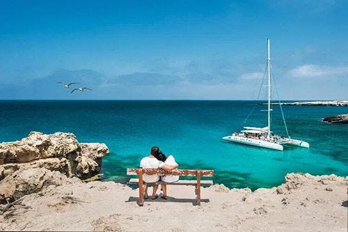 Two people sitting on a bench looking at the sea in Greece