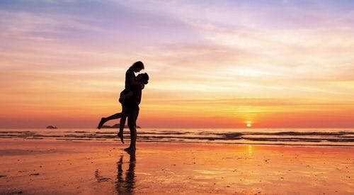 A silhouetted couple embracing on a sunset beach
