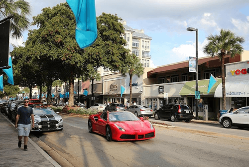 A red Ferrari car driving down the road in a Florida city