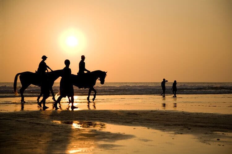 A pair of horse riders enjoy the sunset from a Bali beach