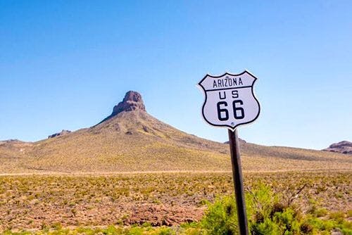 A Route 66 sign in front of a desert rock