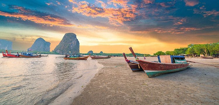 Long=tail fishing boats resting on a white sand beach in Thailand