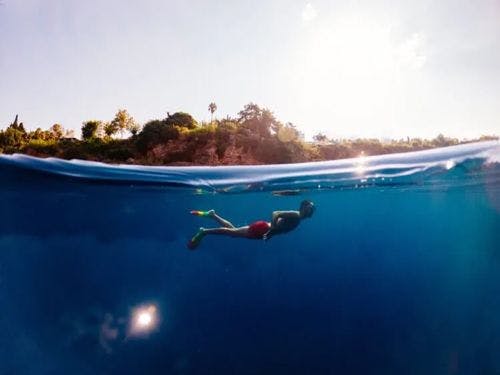 A split image of a person snorkeling beneath the waves